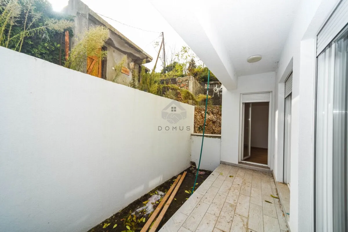 Natkriveni balkon sa popločanim podom i pogledom na dvorište.