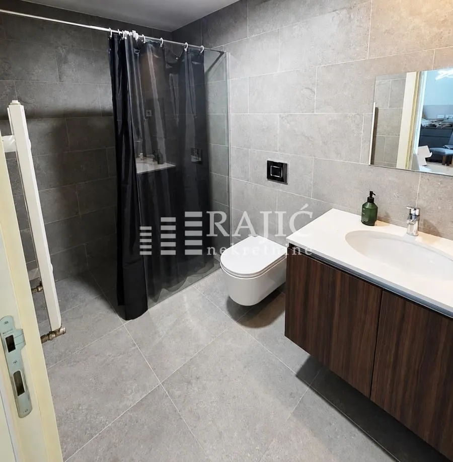 Modern bathroom with a shower cabin, sink, and toilet.