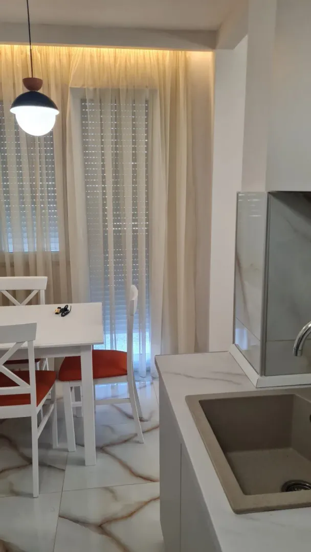 Svijetla kuhinja sa trpezarijskim stolom pored prozora.