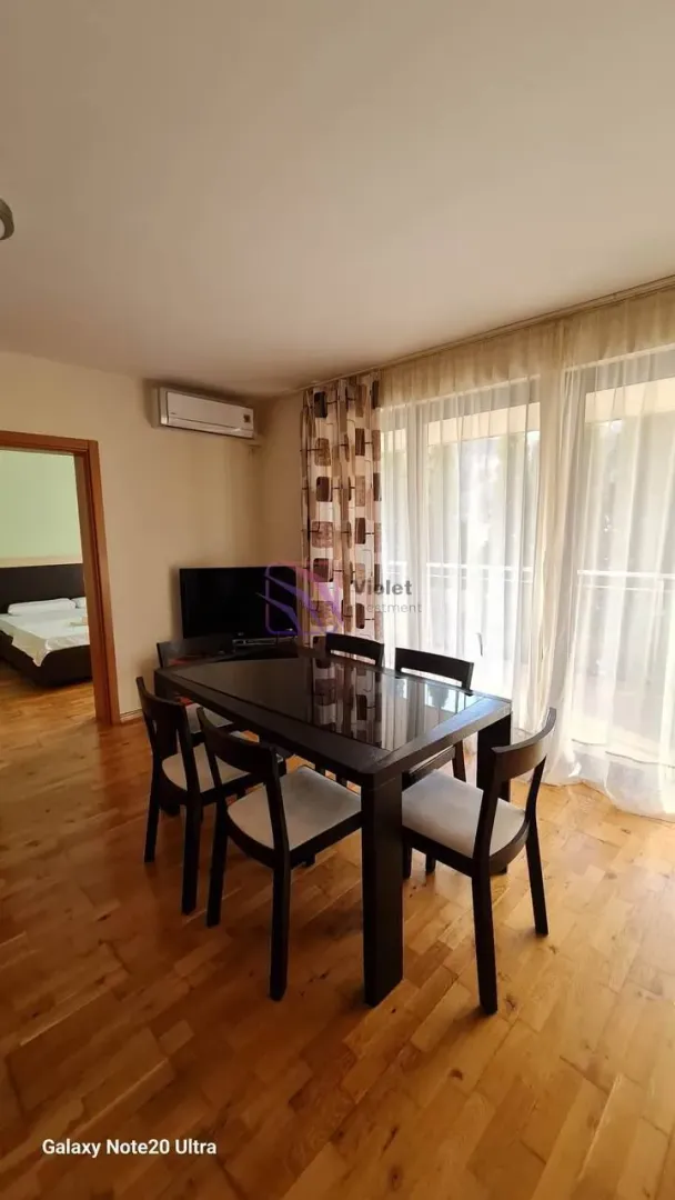 Trpezarija sa stolom i stolicama, parketom na podu i izlazom na terasu.