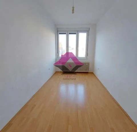 Empty room with white walls, parquet flooring, and a window.