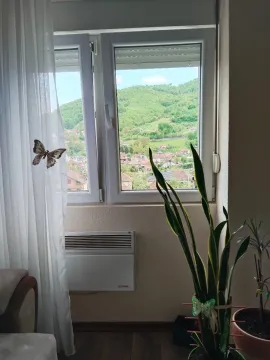 Pogled kroz prozor na okolno naselje i brda. - image 5