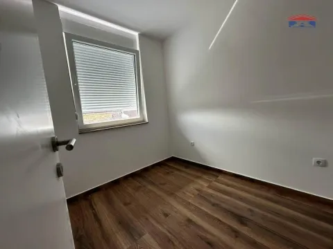 Prazna soba sa belim zidovima, drvenim podom i prozorom. - image 7