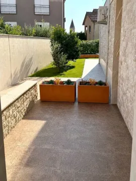 Popločano dvorište sa žardinjerama i uređenom travnatom površinom. - image 4