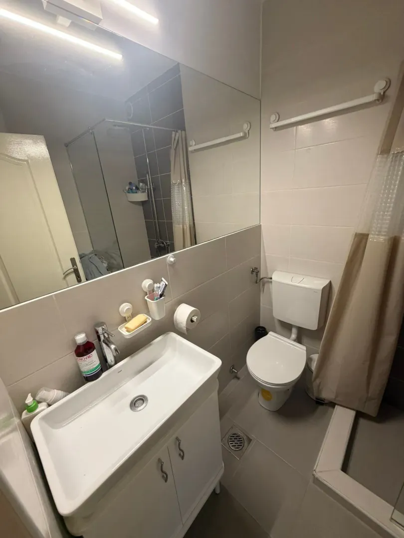 Manje kupatilo sa umivaonikom, WC šoljom i tuš kabinom.