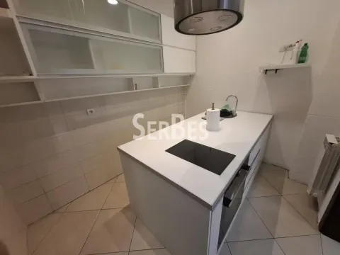 Kitchen with white cabinetry and a kitchen island with a built-in cooktop. - image 7
