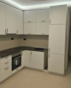Moderna ugaona kuhinja sa bijelim elementima i ugrađenim aparatima. - image 3