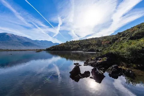 Pogled na jezero i okolne planine sa vedrim nebom. - image 4