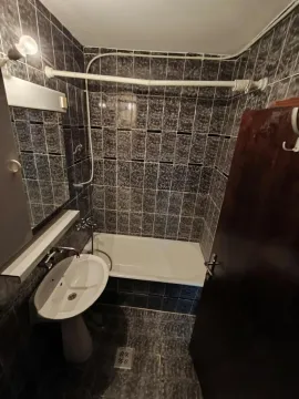 Manje kupatilo obloženo tamnim pločicama sa kadom i umivaonikom. - image 15