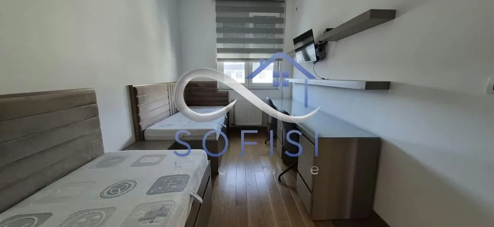 Bedroom with two single beds, a desk, and a TV.