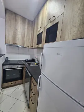 Manja kuhinja sa drvenim elementima, ugradnom rernom i bijelim frižiderom. - image 8