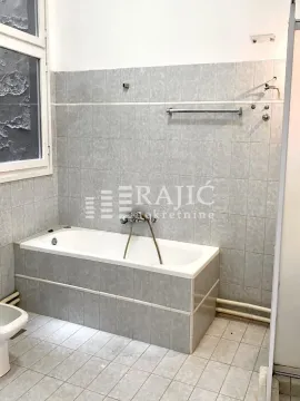 Smaller bathroom with a bathtub and gray wall tiles. - image 15