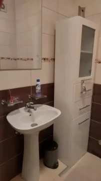 Small bathroom with a sink, mirror, and white cabinet. - image 4