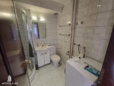 Smaller bathroom with a shower cabin, sink, toilet, and washing machine. - image 11