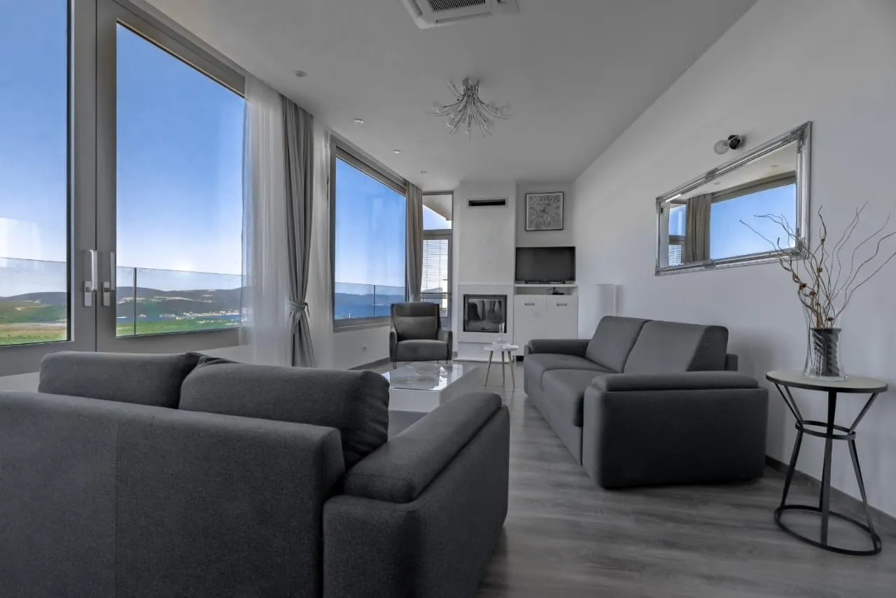 Spacious living room with a seating set and large glass surfaces with a sea view.