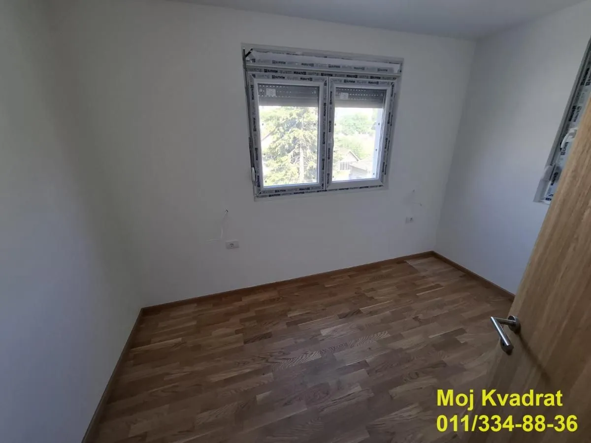 Prazna soba sa parketom i prozorom.