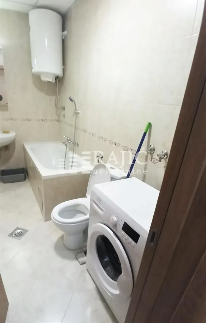 Manje kupatilo sa kadom, toaletom i veš mašinom.