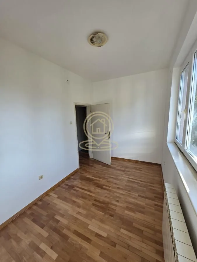 Empty room with parquet flooring and a window.