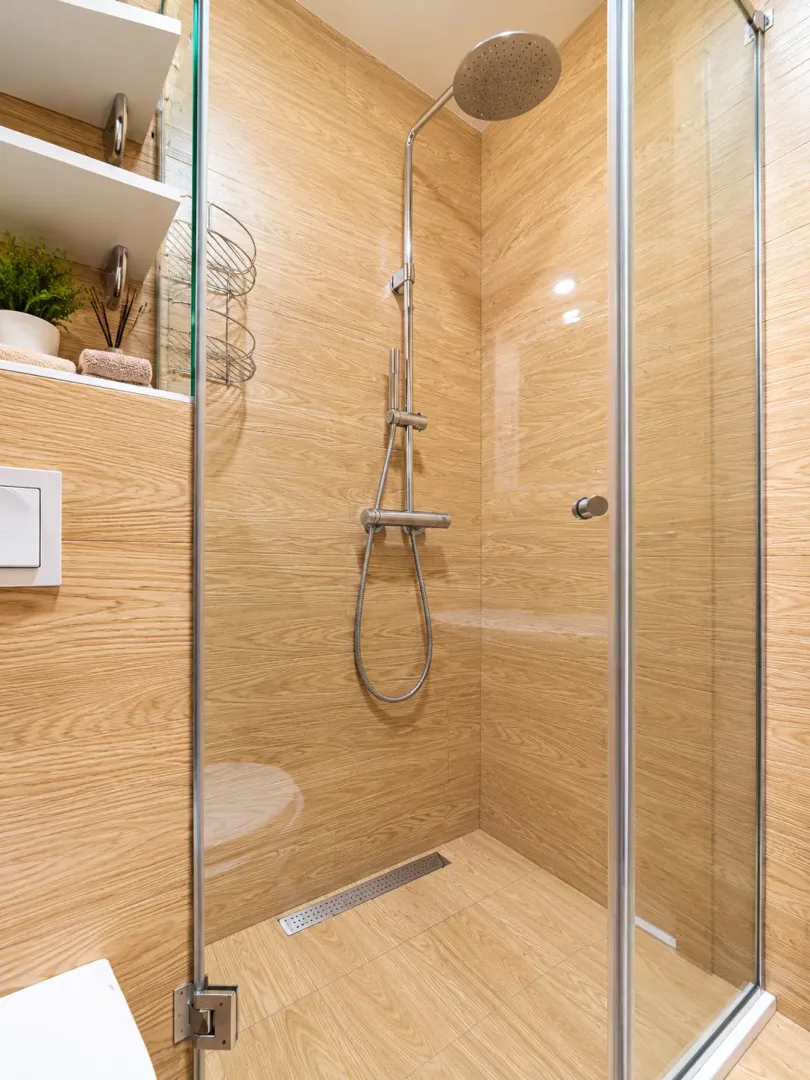 Modern shower cabin with wood-look tiles and a linear drain.