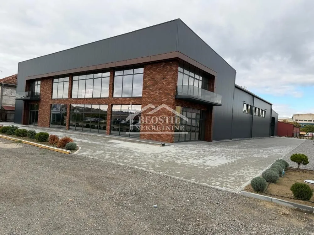 Exterior view of a modern commercial building with large glass surfaces and a paved courtyard.