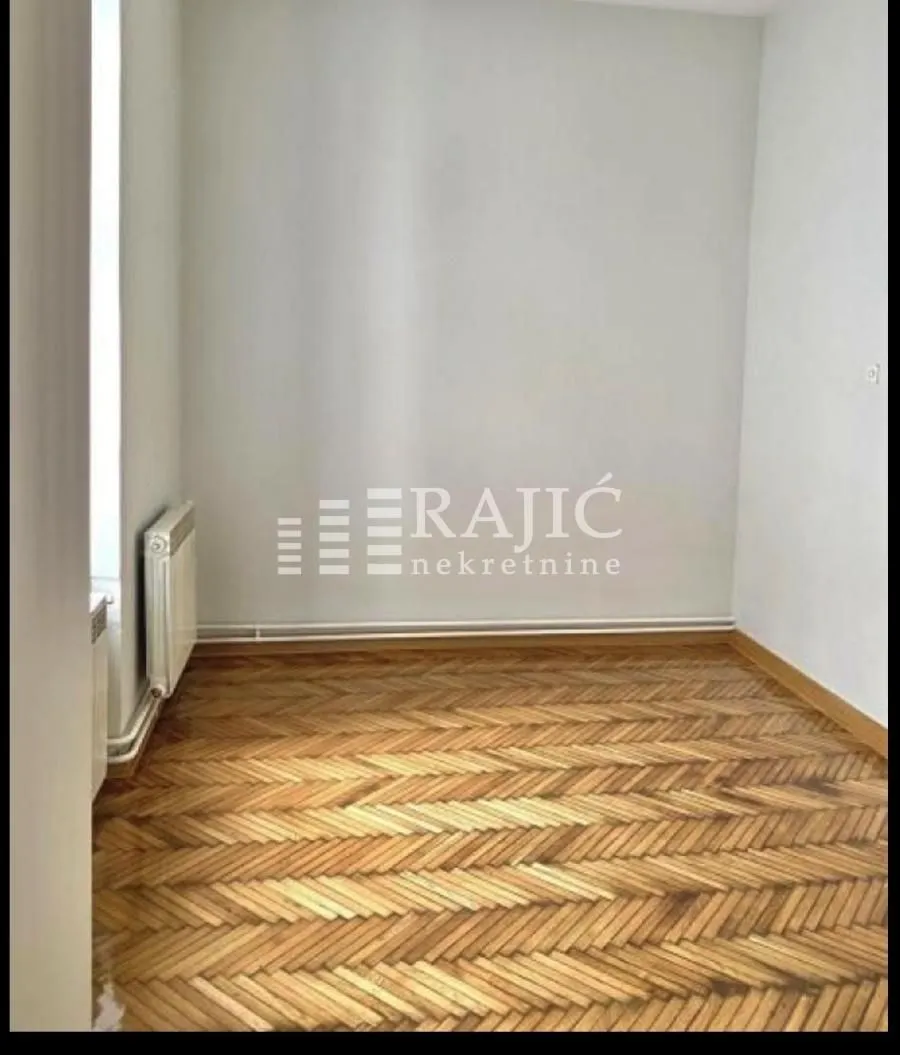 Empty room with parquet flooring and white walls.
