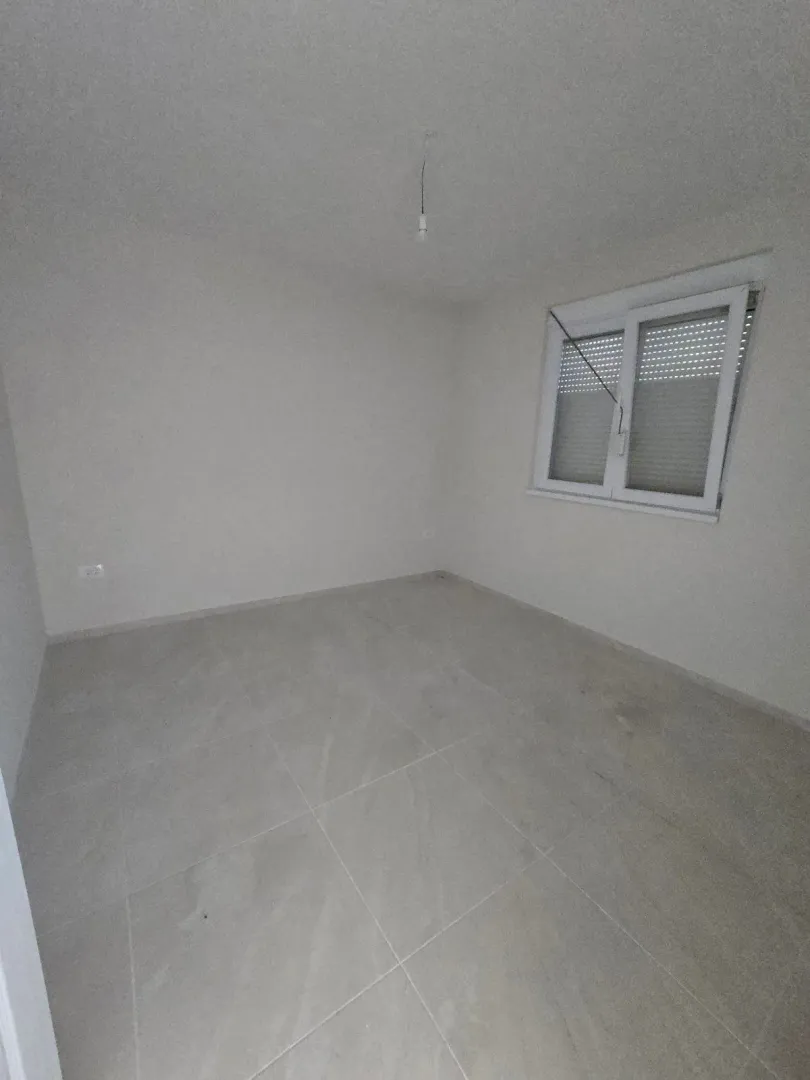 Prazna, tek završena soba sa svijetlim pločicama i prozorom.