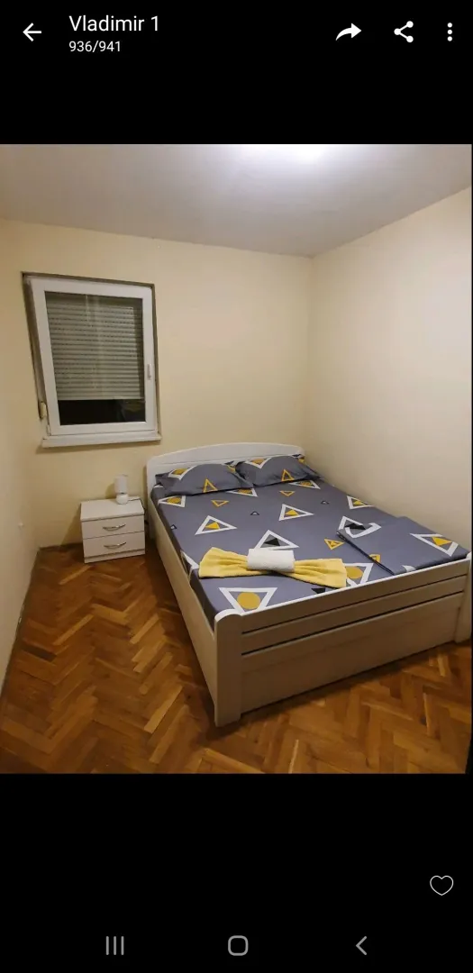 Namještena spavaća soba sa bračnim krevetom i parketom.