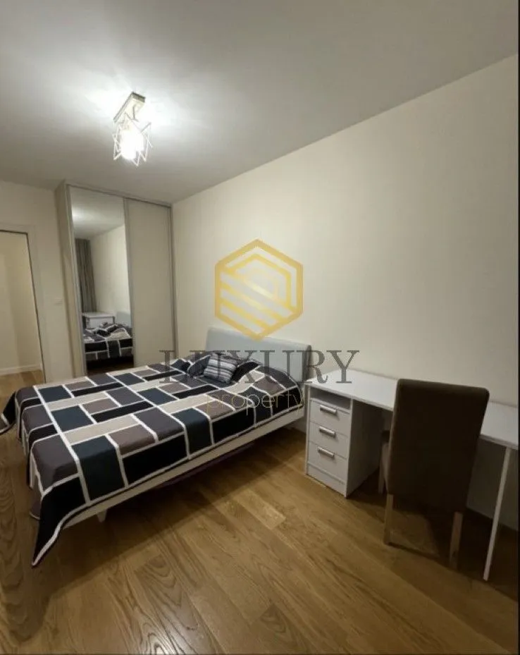 Furnished bedroom with a bed, desk, and mirrored wardrobe.
