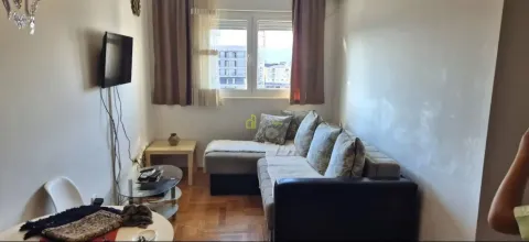 Manja dnevna soba sa garniturom za sjedenje i televizorom na zidu. - image 5