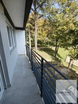 Long balcony with a metal railing and a view of the green courtyard. - image 17