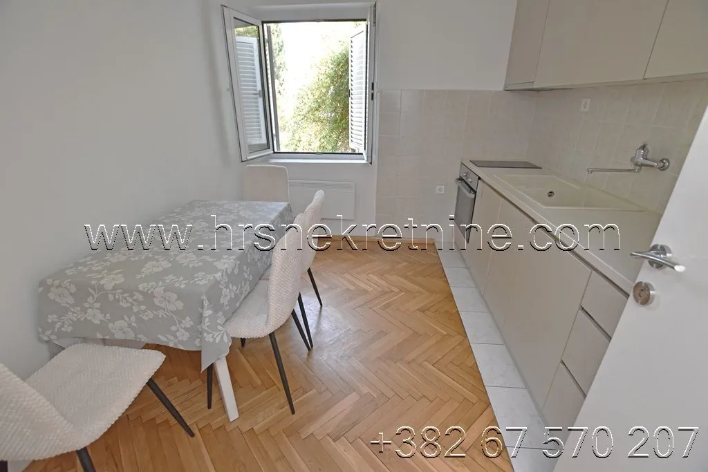 Smaller kitchen with a dining table and parquet flooring.
