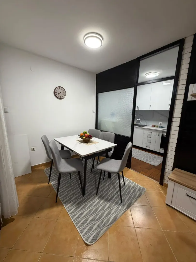 Dining area with a table and chairs, with a view of the kitchen.