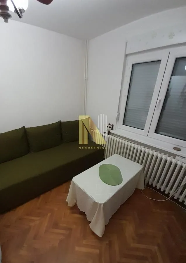 Manja dnevna soba sa zelenom garniturom i belim stočićem.