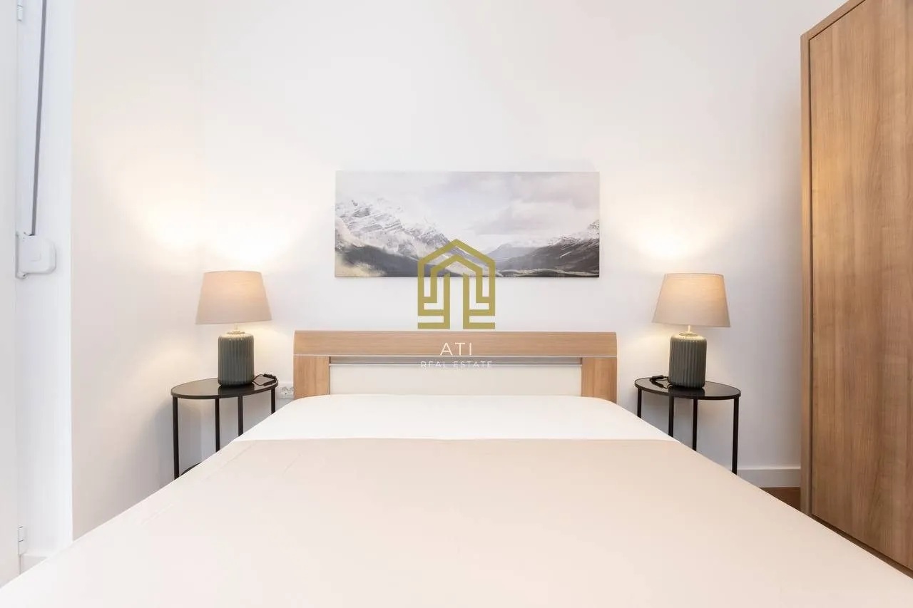 Furnished bedroom with a double bed, bedside tables, and a wardrobe.