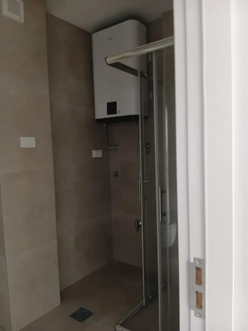 Pogled na kupatilo sa tuš kabinom i bojlerom.
