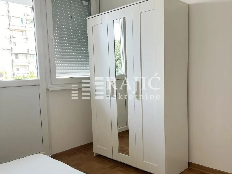 Bedroom with a white wardrobe and a mirror.