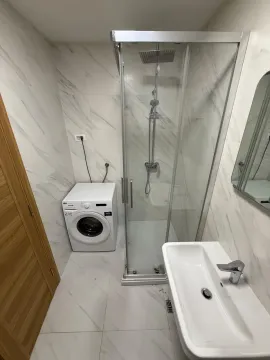 Modern bathroom equipped with a shower cabin and a washing machine. - image 5