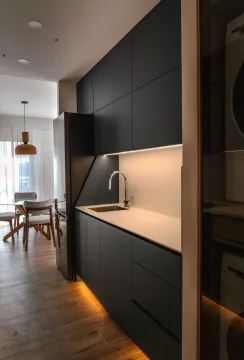 Modern kitchen with dark cabinetry and integrated lighting. - image 3
