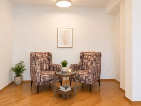 Two armchairs and a small table in a tidy living room with wooden flooring. - image 17