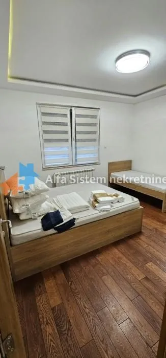 Spavaća soba sa dva kreveta i drvenim podom.