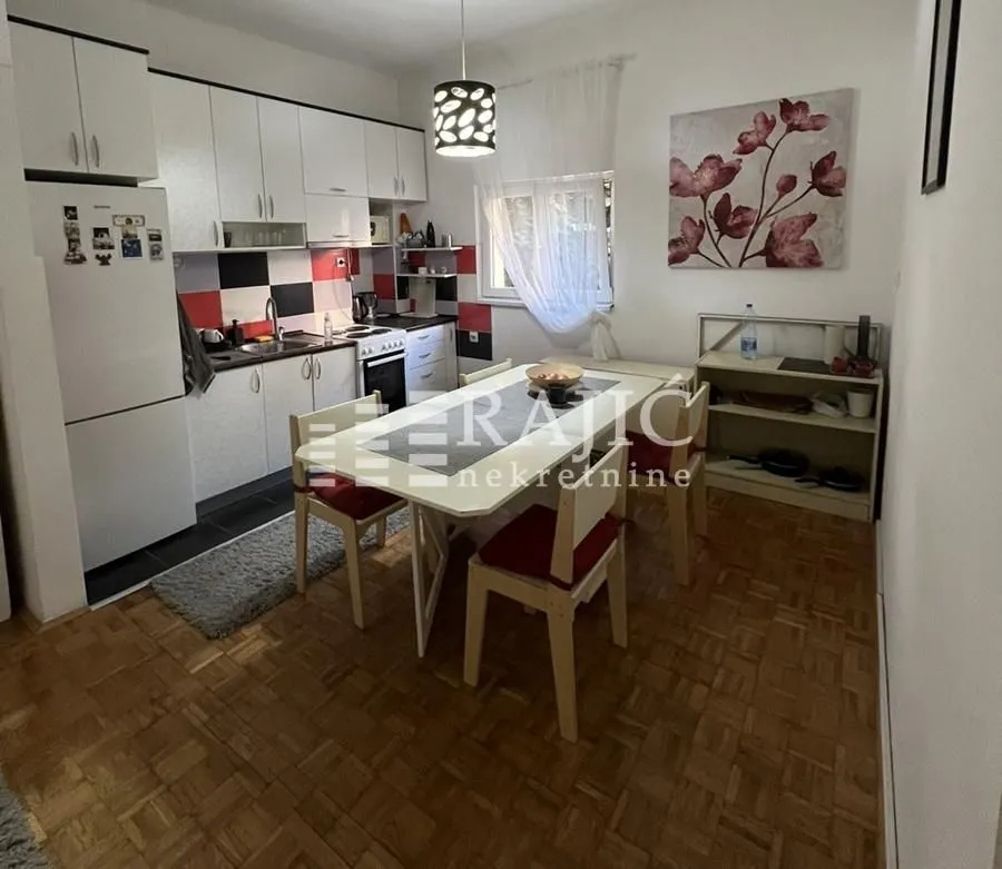 Kitchen with dining area and wooden flooring.