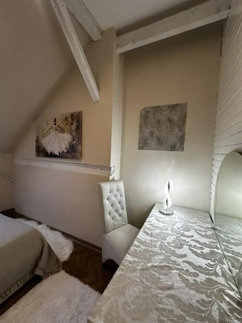 Attic bedroom with sloped ceiling and wooden beams.