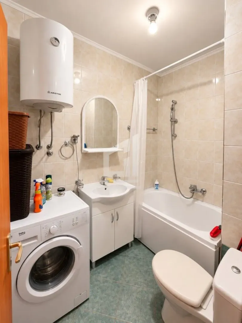 Small bathroom with a bathtub, washbasin, washing machine, and water heater.