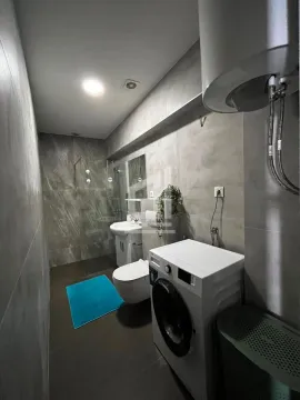 Modern bathroom with a walk-in shower, washbasin, toilet, and washing machine. - image 7