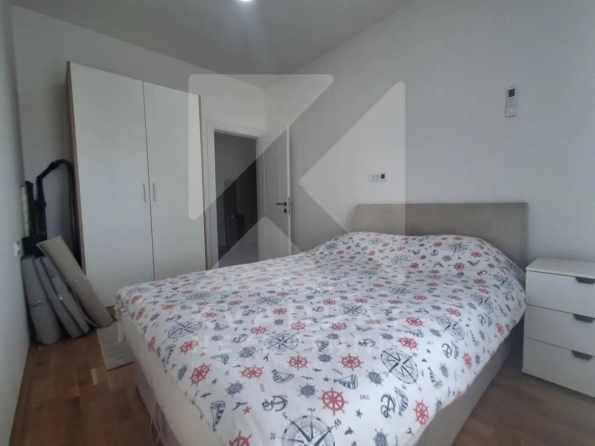 Namještena spavaća soba sa bračnim krevetom, garderoberom i noćnim ormarićem.