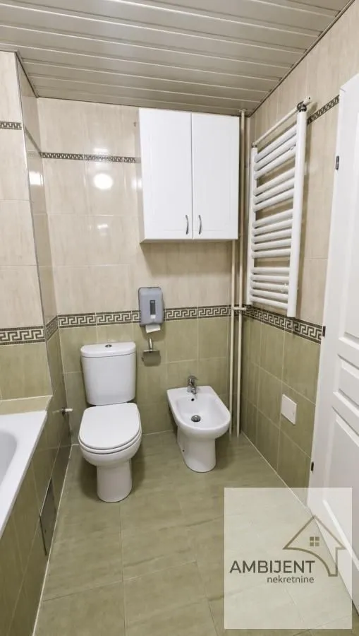 Manje kupatilo sa sanitarijama, bideom i zidnim ormarićem.