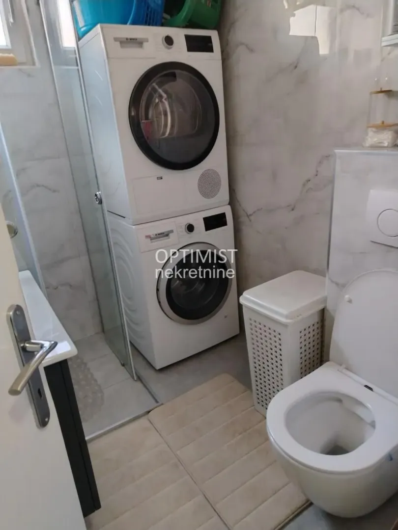 Kupatilo opremljeno tuš kabinom, toaletom i mašinom za veš.