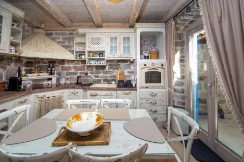 Rustic kitchen with a dining table, wooden beams, and stone walls. - image 5