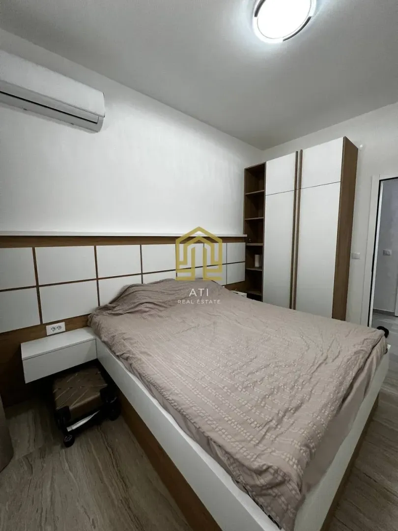 Namještena spavaća soba sa bračnim krevetom i ugradnim plakarom.