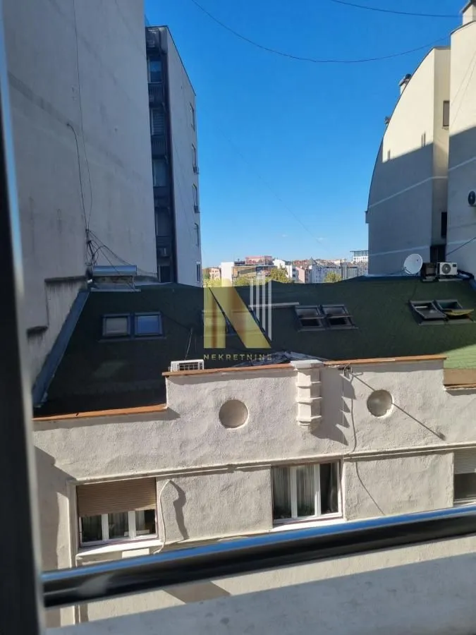 Pogled sa prozora na okolne zgrade i krovove.